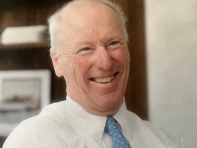 Ted Ladd in a white button down shirt and light blue tie smiling at the camera
