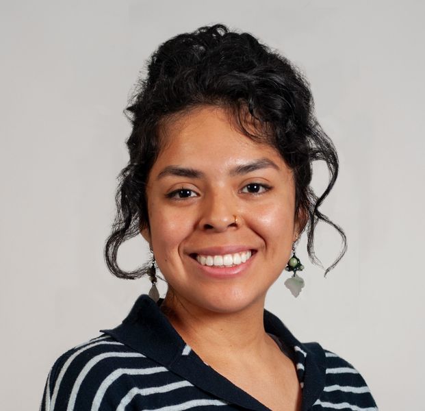 Shows Michelle Bartolo Cruz, who is wearing a blue and grey striped shirt and has dark hair that she is wearing up