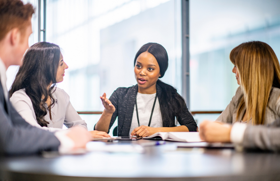 Young women leading meeting around a table with other professionals