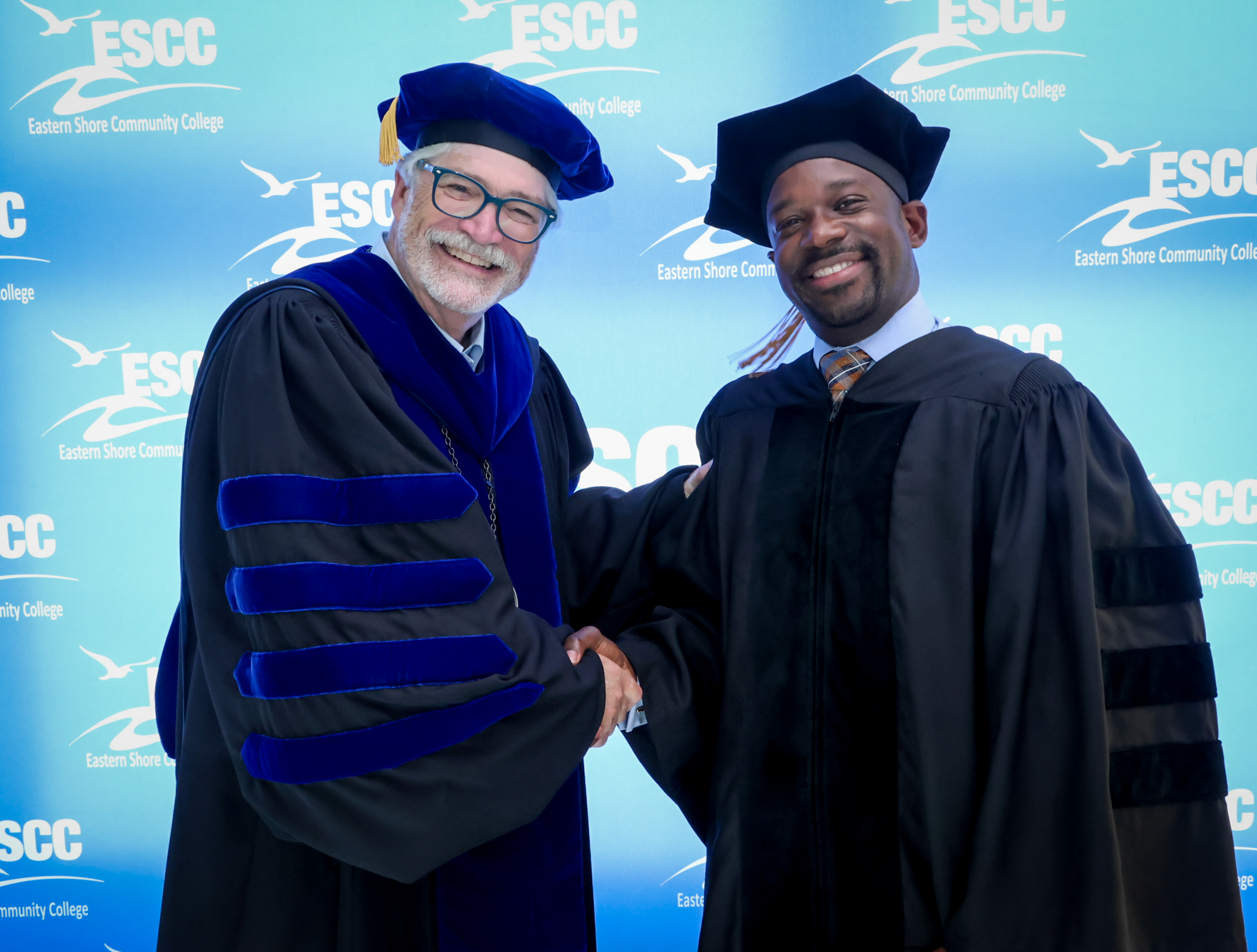 Jim Shaeffer shaking the hand of fellow ESCC community member in regalia