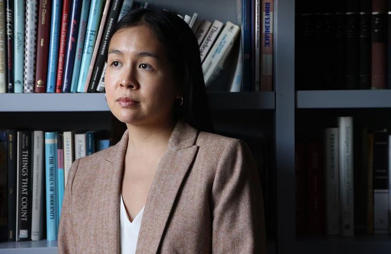 Shows professor Olivia Chi standing in front of a shelf full of books