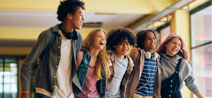 5 middle school students smiling walking arm and arm