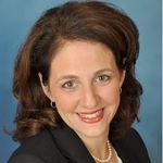 Shows Donna Pincus, who has shoulder length brown hair and is wearing a dark jacket and light top