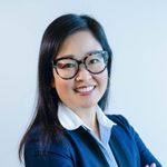 Shows Erin Hashimoto Martell, who has long black hair and is wearing glasses and a blue jacket over a collared shirt