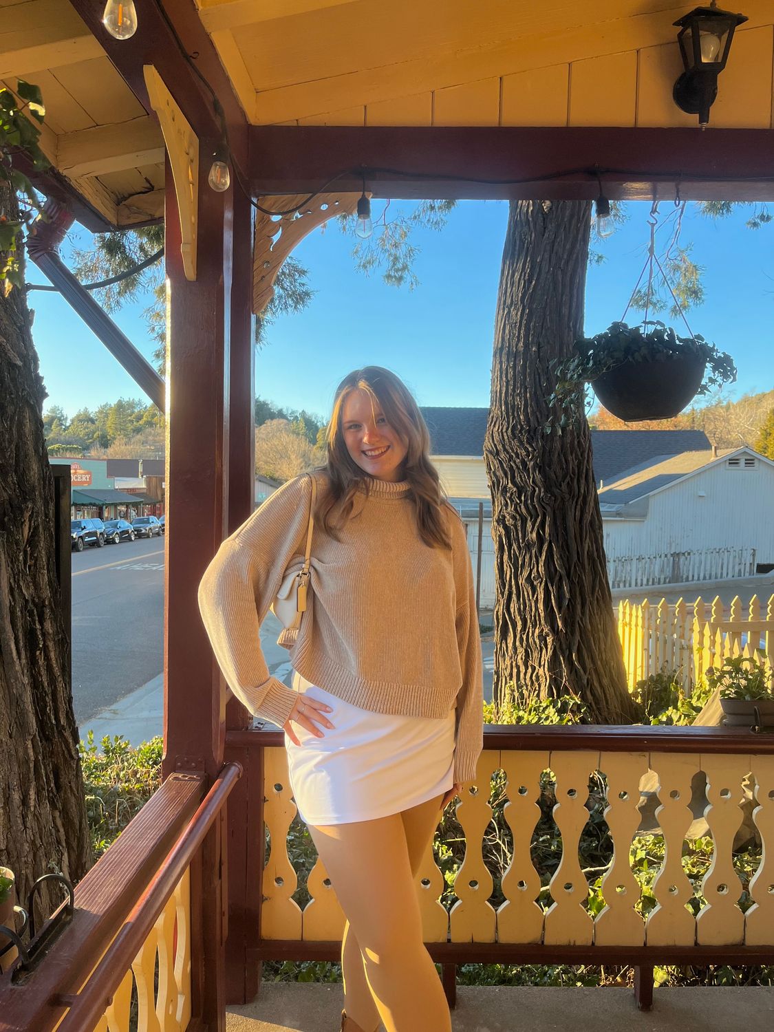 blonde female student smiling on front porch of house