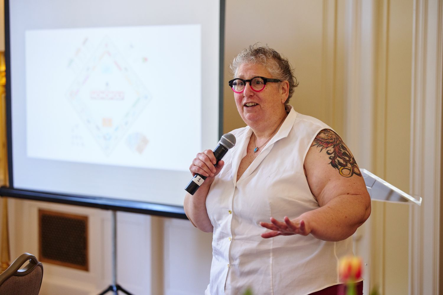 A woman is holding a microphone and speaking to a group