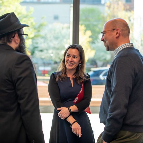Three faculty members are having a discussion near a window.